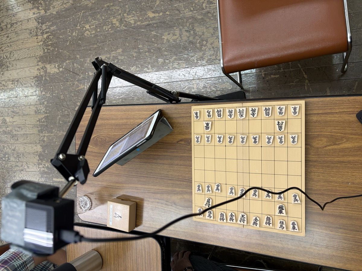卓上の機材一式。アームに載せたアクションカメラが盤を見下ろし、脇のiPadに認識結果が映る